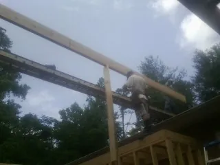 Carpenter setting a ridge beam over a new addition frame — Ice Dam Removal by Roofing Brothers in Maskell