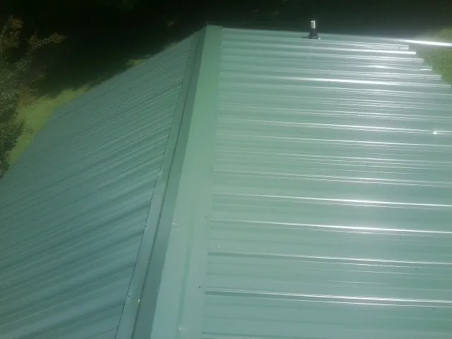 New green metal panels meeting at the ridge of a roof — Flat Roof Repair work by our crew in Maskell