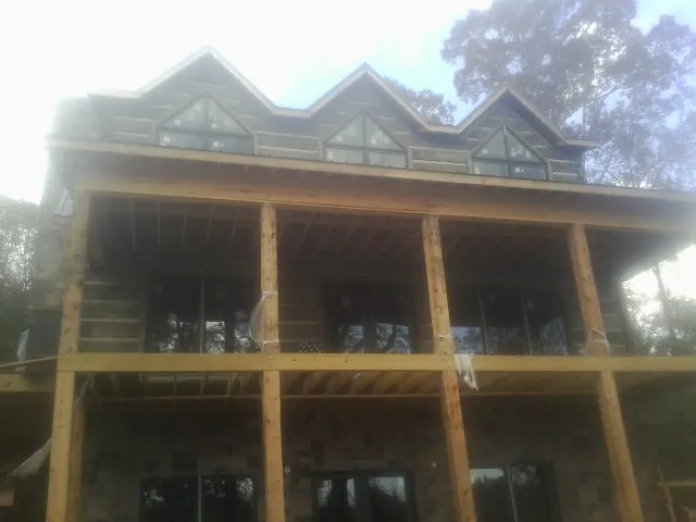 Dormers and porch framing on a large log home under construction — Roof Coating work by our crew in Maskell