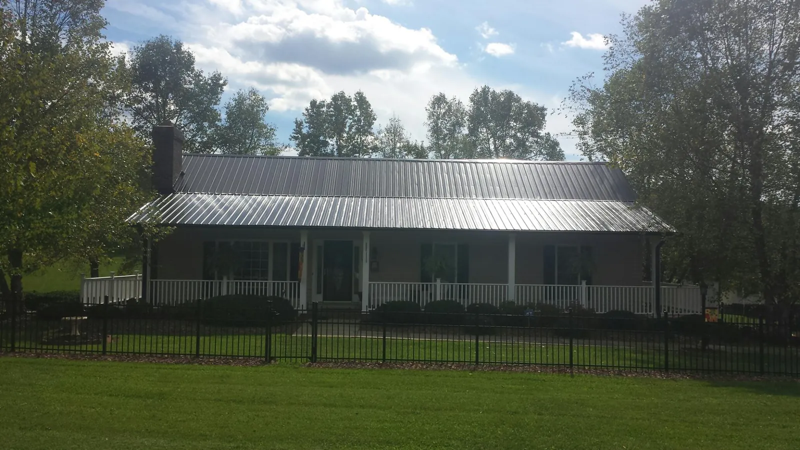 Gray metal roof on a brick ranch with a full width front porch — Gutter Guard Installation work by our crew in Maskell